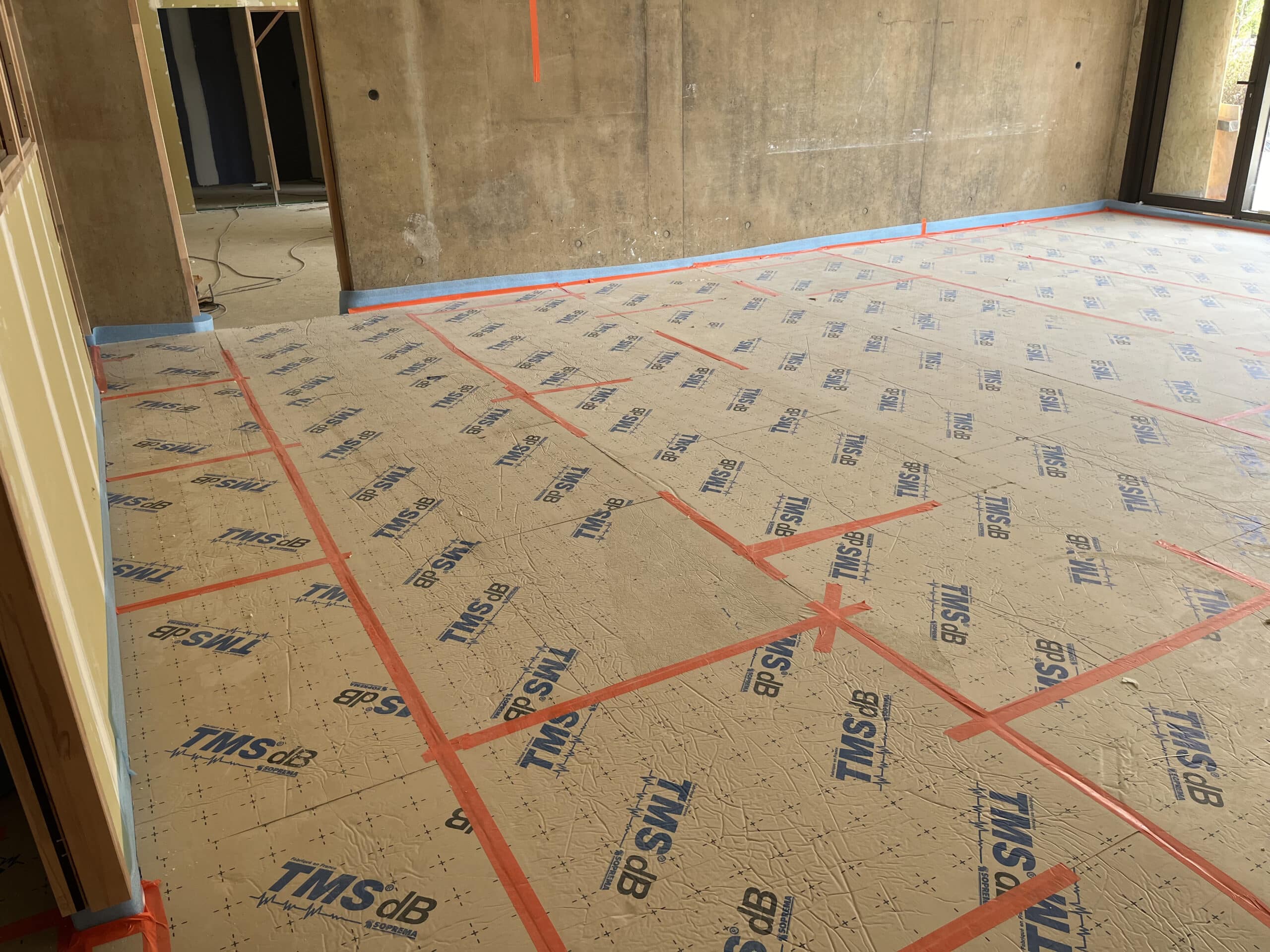 Panneaux isolants TMS dB posés au sol avec joints adhésifs orange, avant coulage de la chape